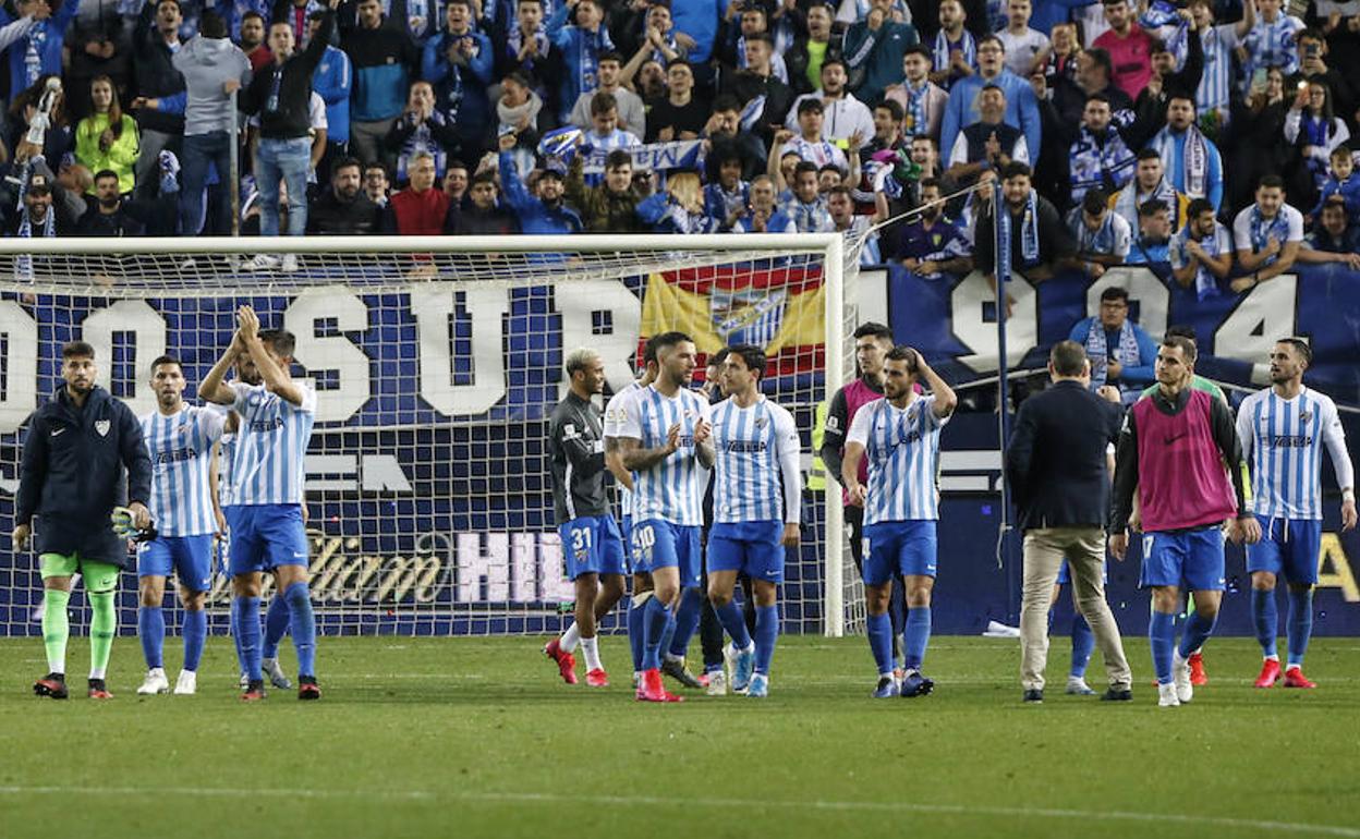 Jugadores del Málaga aplauden en el césped de La Rosaleda tras su victoria contra el Racing.