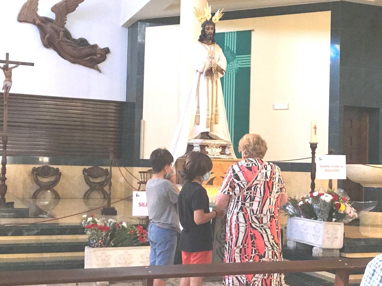 Una señora, con sus nietos, reza al Cautivo tras depositar flores el pasado viernes por la tarde en la Amargura. félix lorenzo
