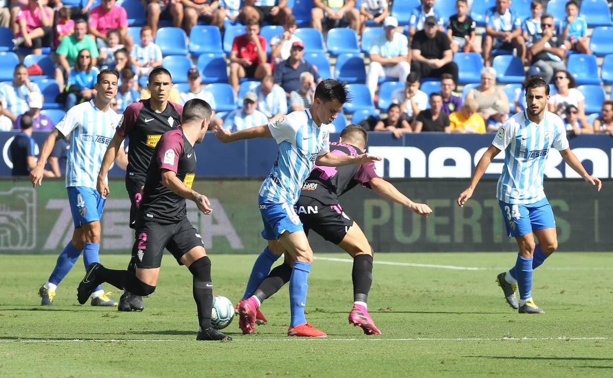 Juanpi intenta controlar el balón, con Luis Hernández y Luis Muñoz, en el último Málaga-Sporting. 