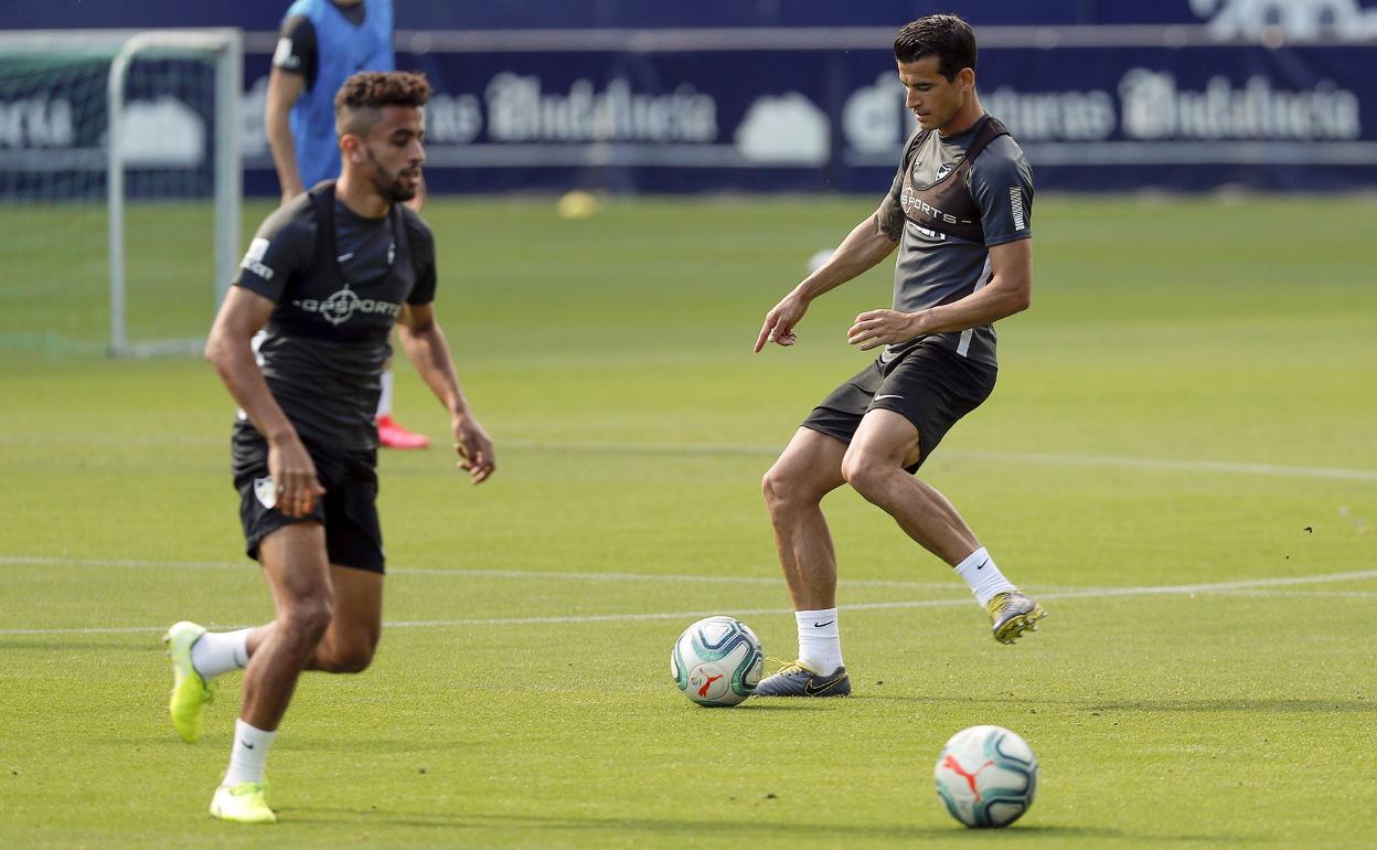 Al fondo, Luis Hernández pasa un balón cerca de Benkhemassa, que aparece fuera de foco.
