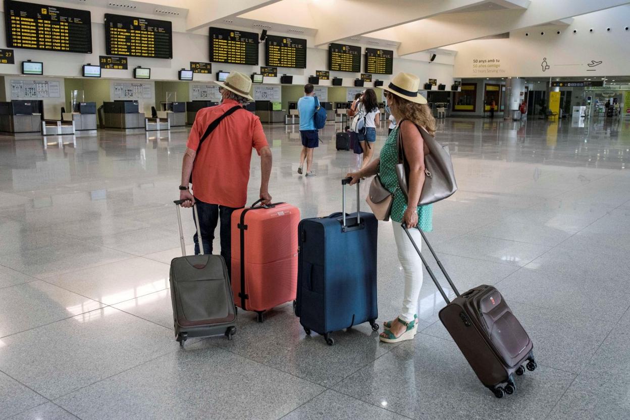 Viajeros mirando los paneles de vuelo en el aeropuerto de Palma de Mallorca. efe