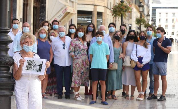 Imagen principal - Arriba, Remedios posa con su extensa familia en segundo término. En sus manos sostiene una fotografía de calle Larios de 1937, año en que se mudó a la calle. Abajo, a la izquierda, en el comedor de su casa, que hace años acogió la consulta de su hermano, Adolfo. Al lado, Remedios muestra una fotografía suya, cuando tenía 18 años 