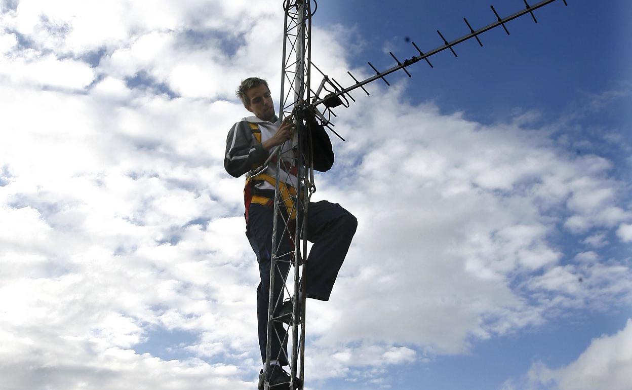 Un instalador sobre una antena de televisión. 