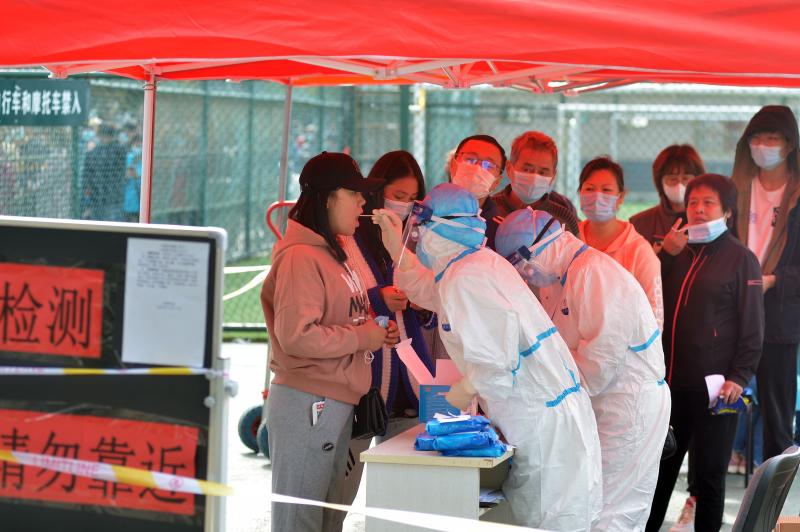 Un personal médico toma muestras de los ciudadanos que hacen fila para la prueba masiva en Qingdao 