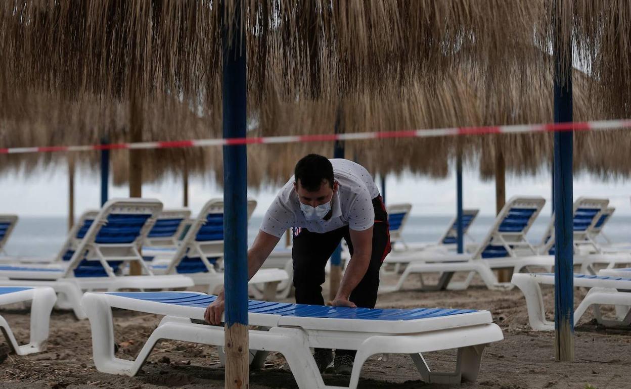 Un trabajador de un chiringuito coloca una hamaca este verano en la Costa del Sol. 