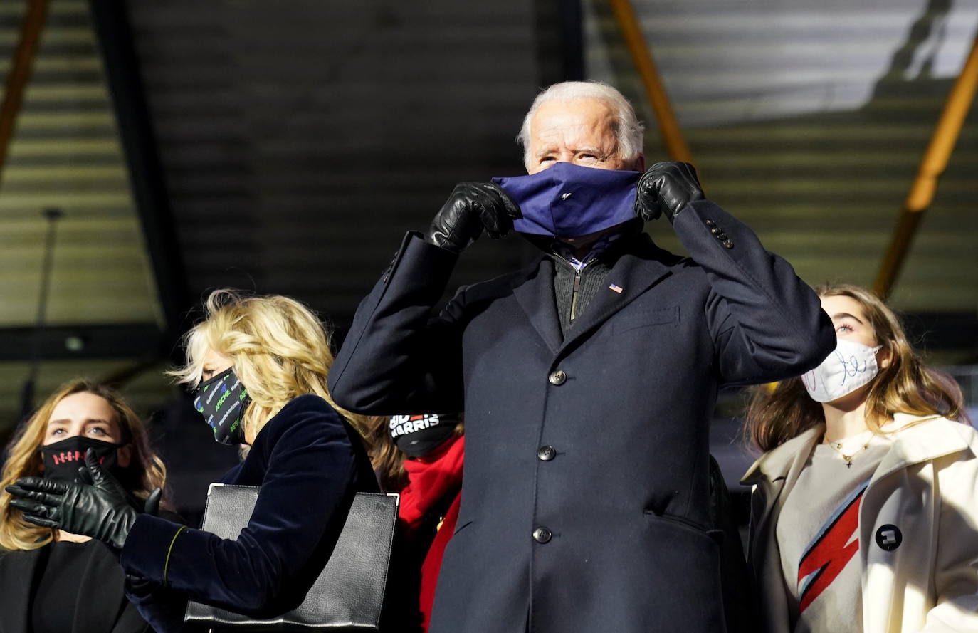 El candidato demócrata a la presidencia de Estados Unidos y exvicepresidente Joe Biden se pone una mascarilla mientras está de pie en el escenario con su familia durante un mitin de campaña en el Heinz Field en Pittsburgh, Pensilvania, EE. UU.