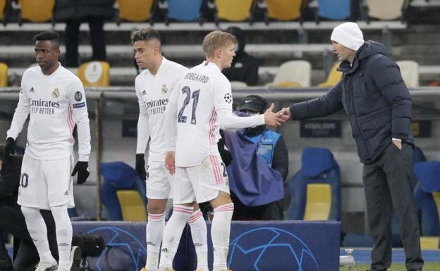 Odegaard estrecha la mano de Zidane, con Vinicius y Mariano aguardando su turno en la banda. 