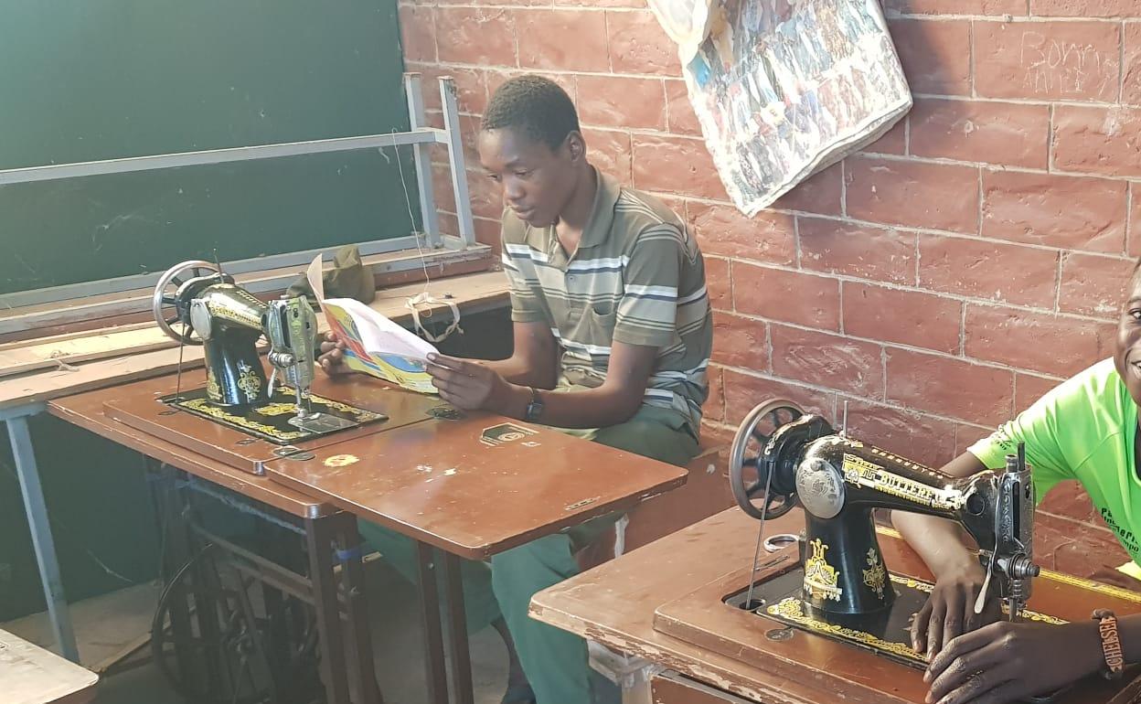 Dos jóvenes realizan labores de costura en el centro de acogida.