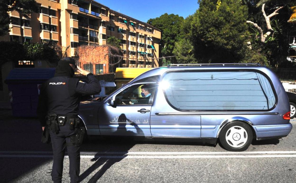 Un policía nacional saluda al coche fúnebre que transporta los restos mortales del agente Antonio Jesús Martín. 