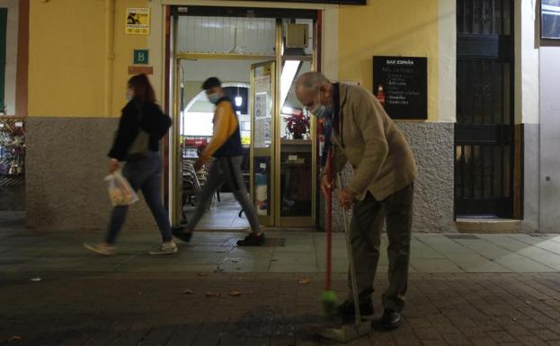 Un camarero barre la puerta de un negocio