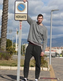 Imagen secundaria 2 - Rubén Guerrero, en un partido del Unicaja, en el gimnasio con unas pesas y demostrando su altura (2,12 metros) junto a una señal de aparcamiento vertical. 