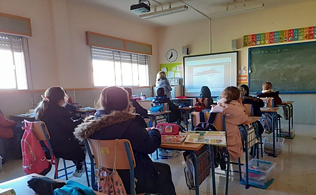Un aula, con ventanas abiertas y los alumnos, abrigados. 