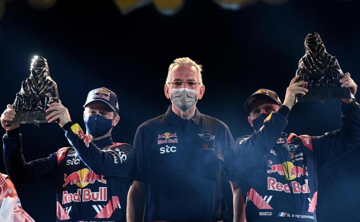 Stephane Peterhansel (d) y su copiloto, Édouard Boulanger (i), reciben los trofeos del Dakar 2021 junto a Jean Todt, presidente de la FIA.