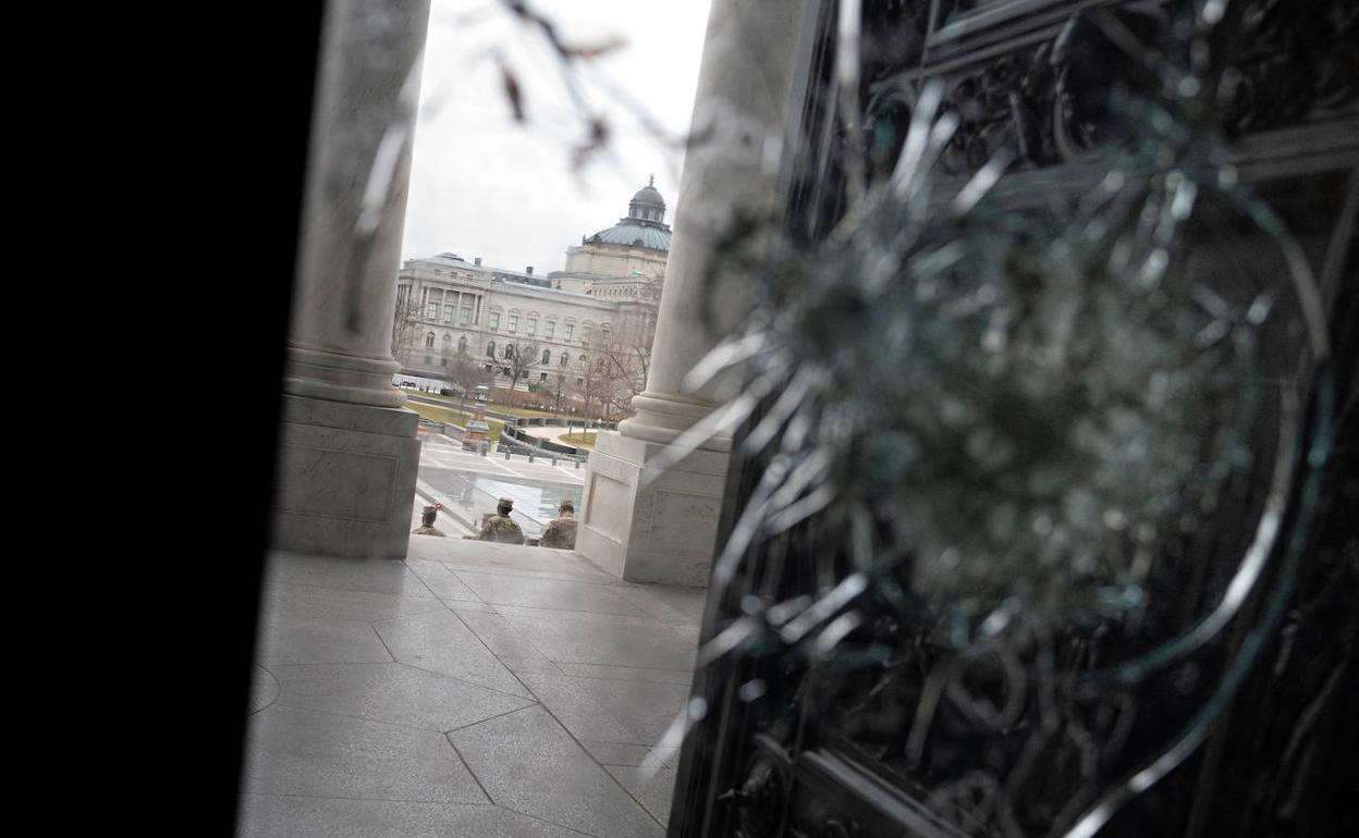 La Guardia Nacional controla el perímetro del Capitolio, vista desde una puerta rota tras el asalto de los seguidores de Trump.