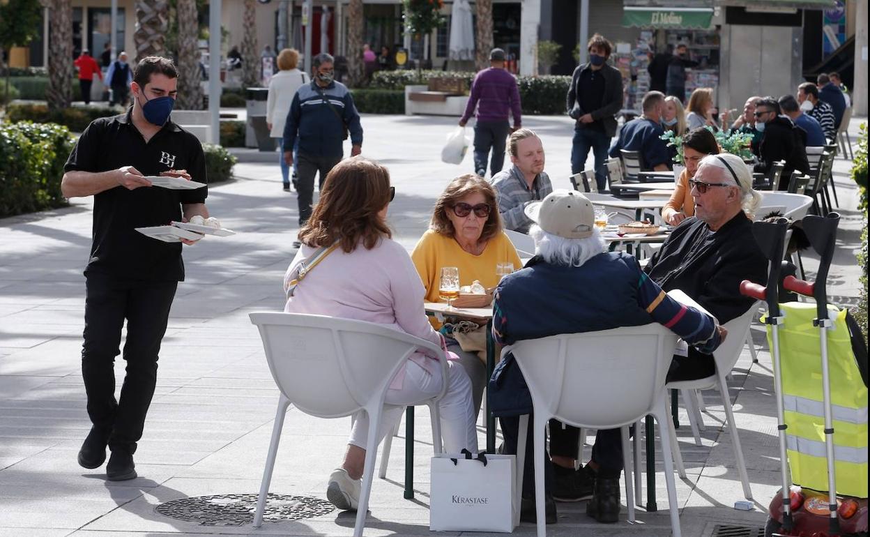 Un camarero se dirige a una de las mesas de la terraza con la comanda solicitada. 