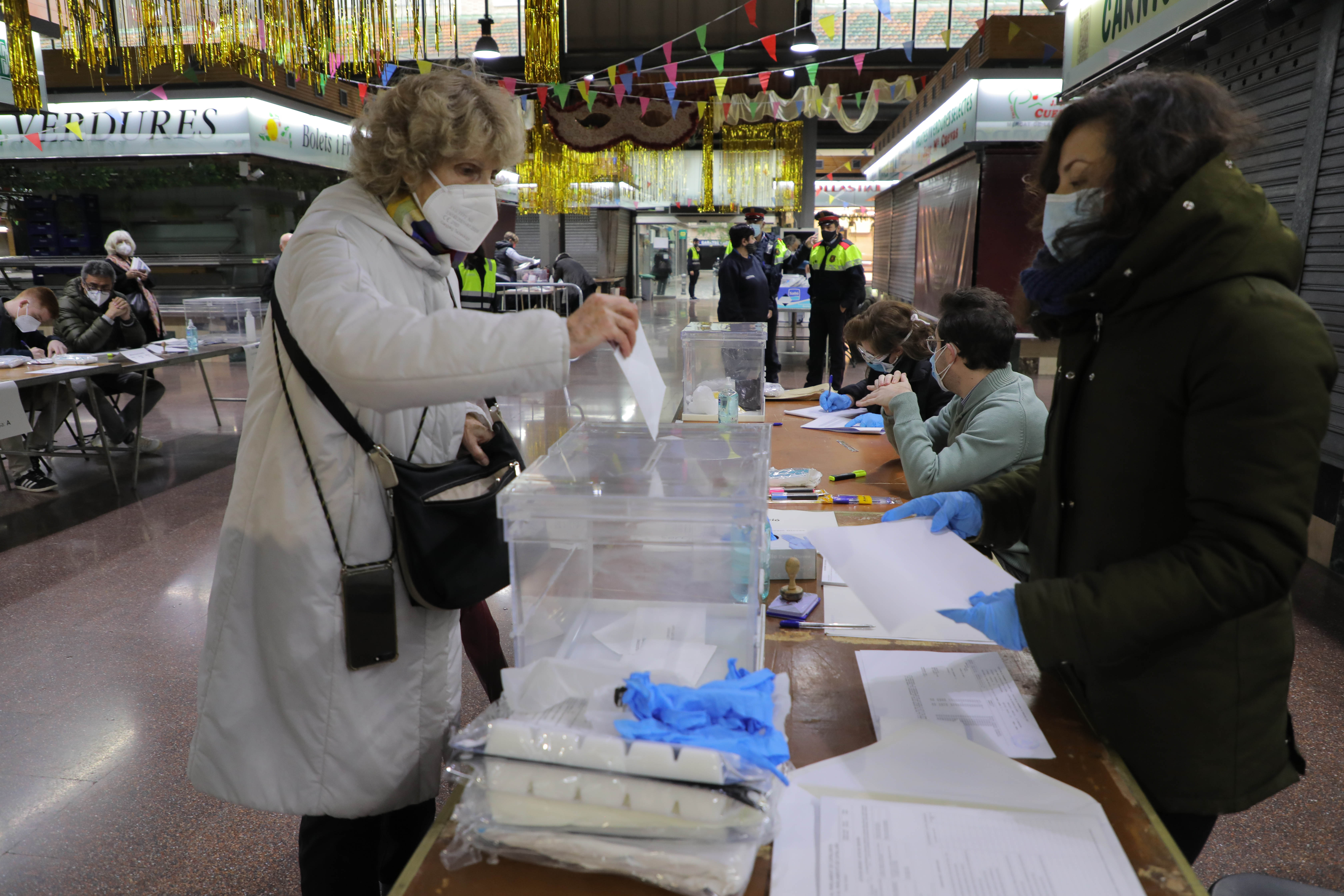 Una mujer ejerce su derecho a voto en una mesa electoral del mercado de la Concepciò, en la que se pueden ver las medidas de seguridad.