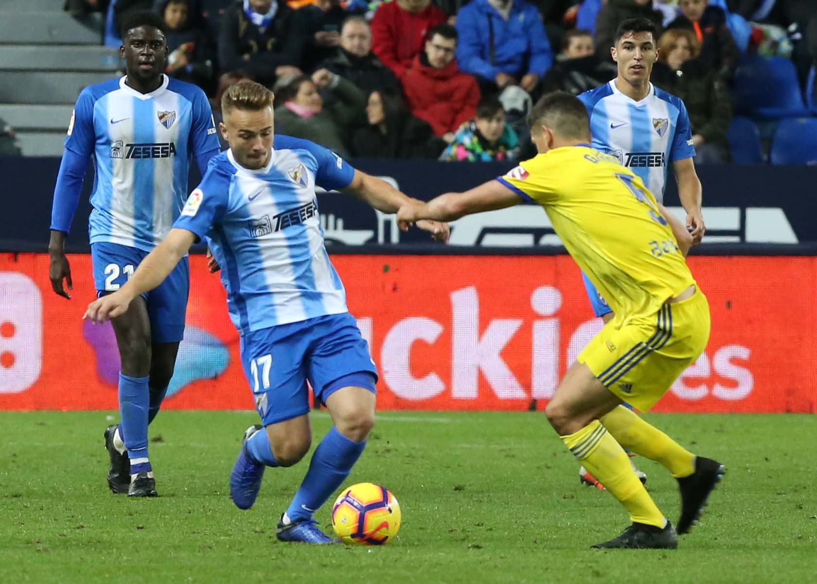 Ontiveros conduce un balón en un partido de la temporada 18-19 contra el Cádiz en La Rosaleda con N'Diaye al fondo.