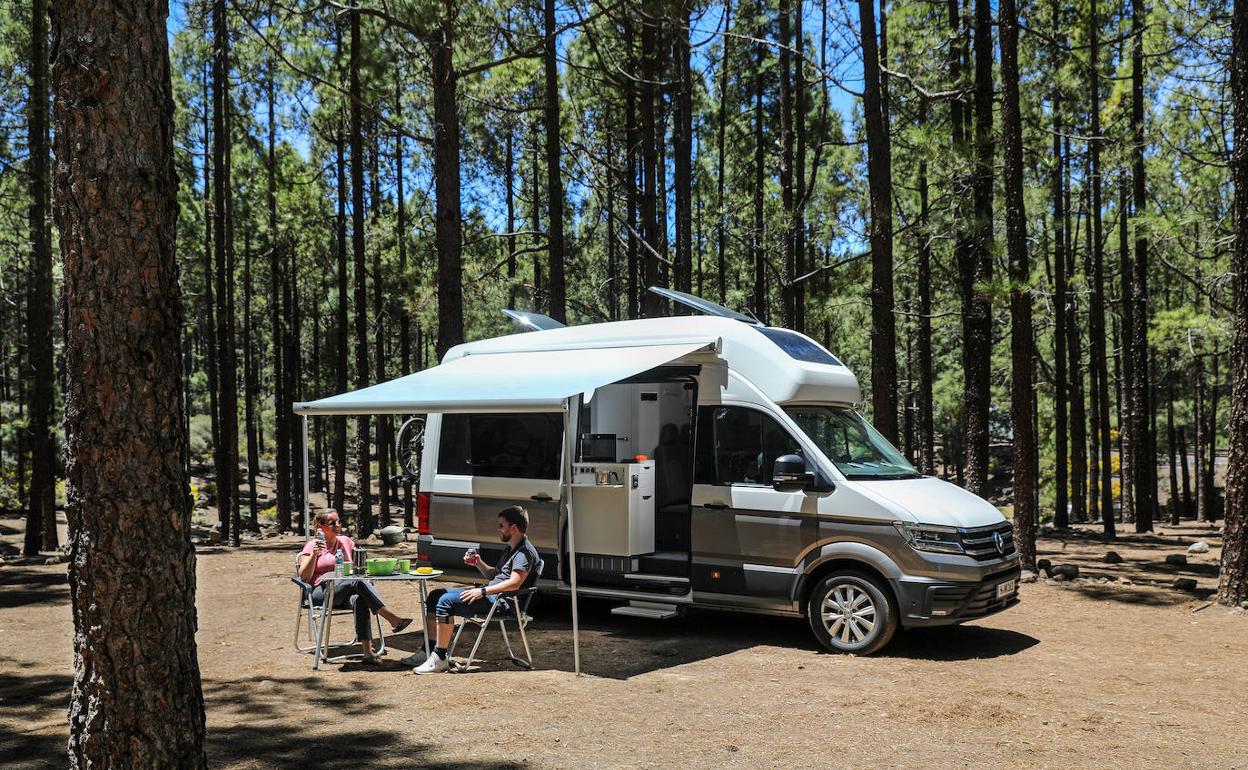 Una pareja con una furgoneta camper en el bosque.