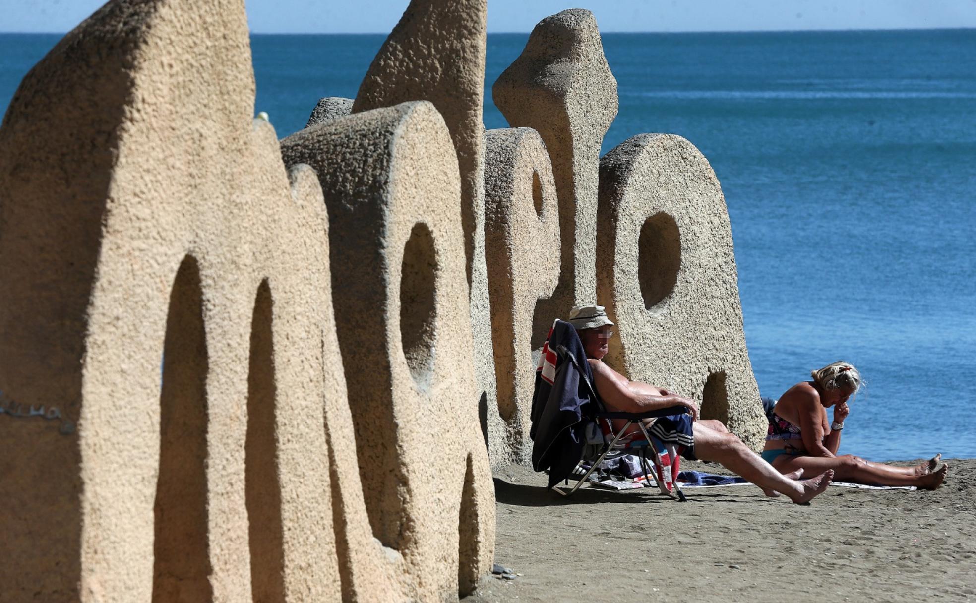 Una pareja toma el sol junto a las letras de la playa de La Malagueta, en la capital. 