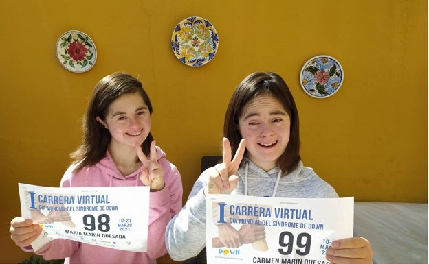 María y Carmen muestran su dorsal de la carrera.