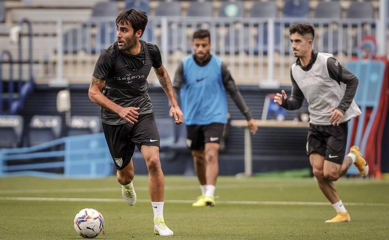 Escassi, pilar del equipo, conduce el balón durante un entrenamiento de esta semana con Julio y Benkhemassa al fondo. 