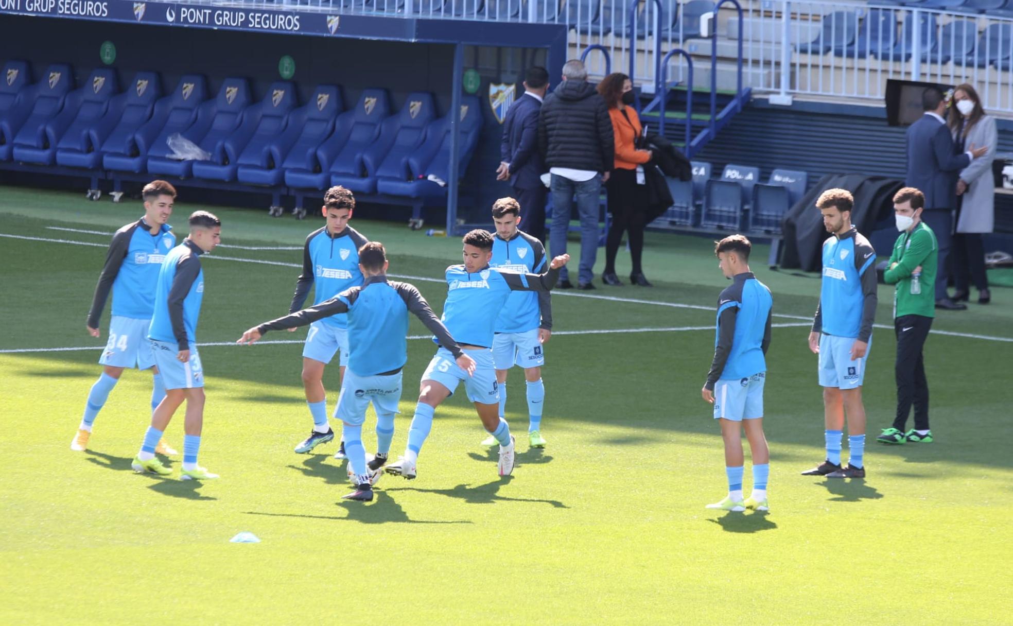 Algunos de los canteranos habituales del primer equipo calientan durante la previa de un partido de esta temporada en La Rosaleda.