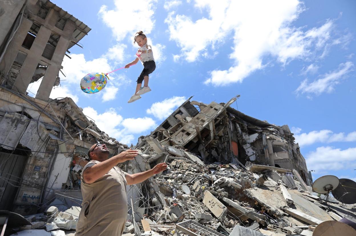 Un palestino juega con una niña junto a los escombros provocados por los bombardeos en Gaza. Ashraf Amra / e. p.