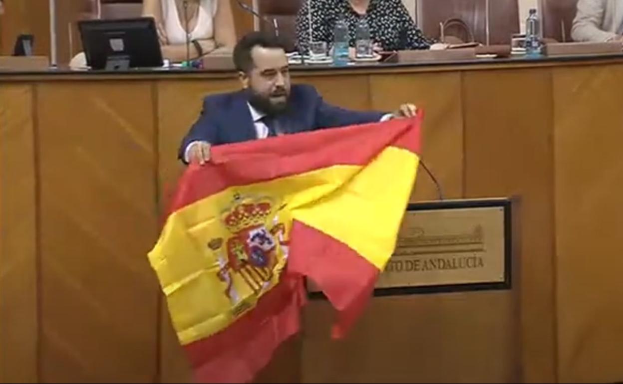 El parlamentario de Ciudadanos Fran Carrillo despliega una bandera durante su intervención.