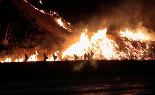 Un grupo de bomberos trata de extinguir un incendio en un valle de California. 