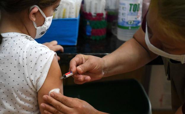 Un médico vacuna a una niña.