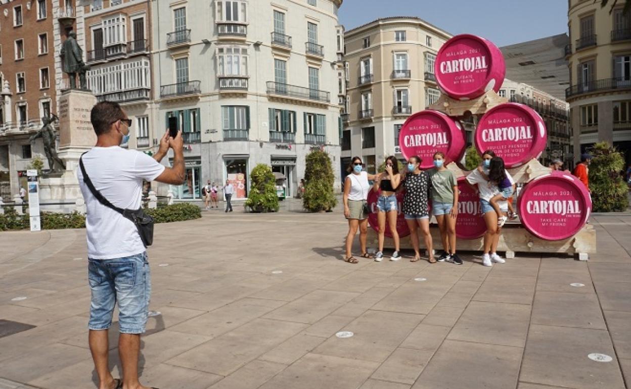 Un grupo de amigas posa ante los barriles de Cartojal que se han colocado a la entrada de la calle Larios. 