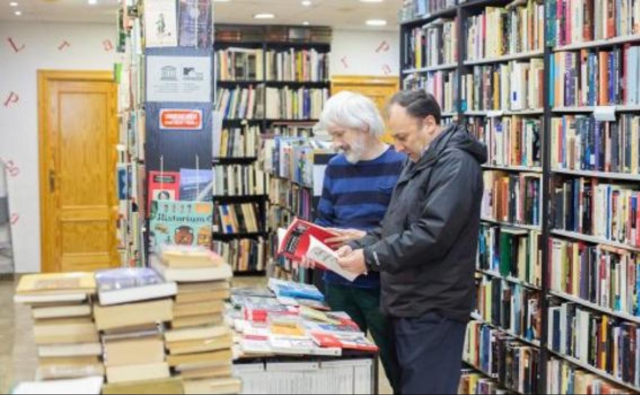 Dos lectores hojean libros en una librería granadina.