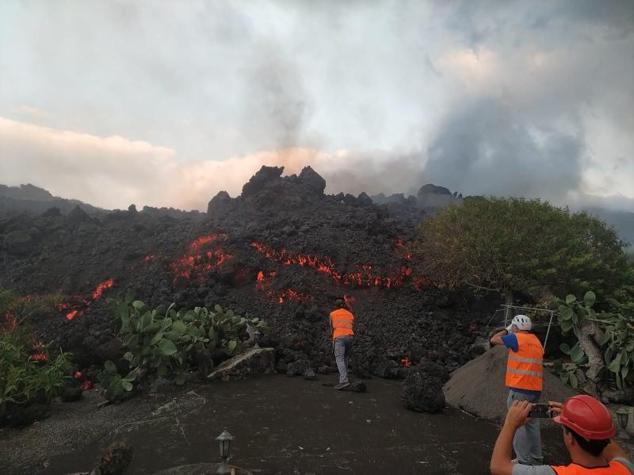 Técnicos del Instituto Volcanológico de Canarias toman muestras de las coladas de lava del volcán para realizar análisis petrológicos.