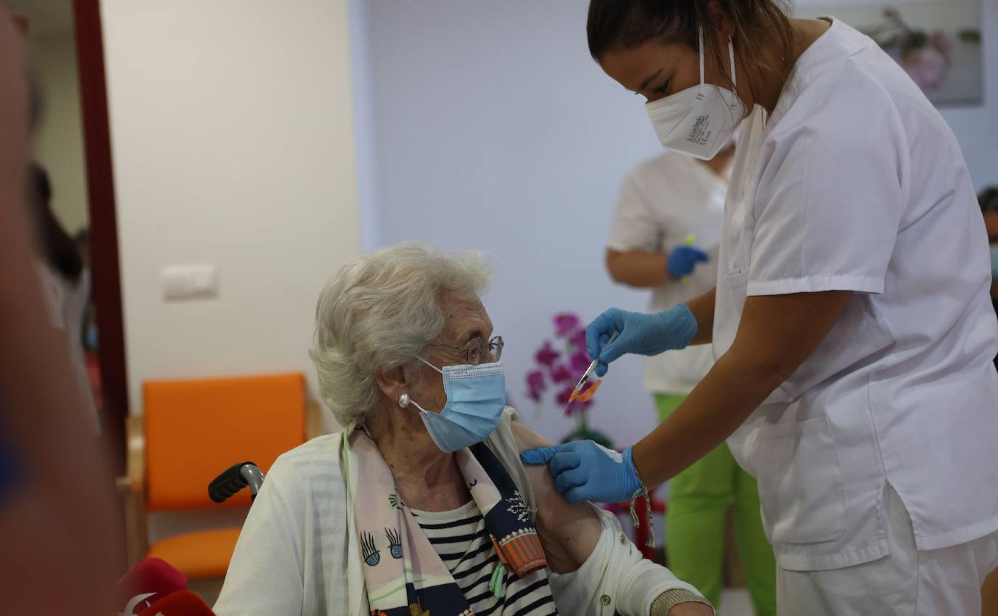 Una sanitaria vacuna a una mujer en una residencia. 