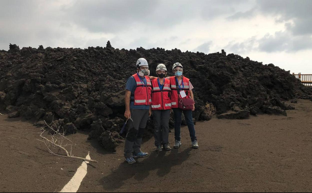 María José Blanco, en el centro, junto a sus dos compañeros del Instituto Geográfico Nacional, posan ante la colada de lava en La Palma.