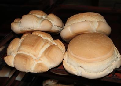 Imagen secundaria 1 - Paqui Astorga enseña el típico mollete de la panadería. Abajo, panes de canto y lisos.