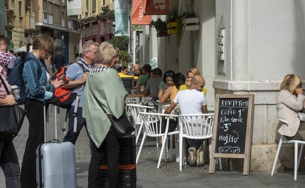 Turistas pasan por delante de un bar del Centro. 