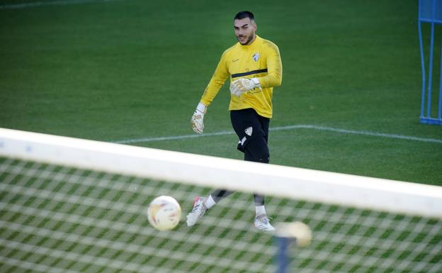 El portero del Málaga, Dani Martín, golpea el balón durante el entrenamiento de ayer en La Rosaleda.