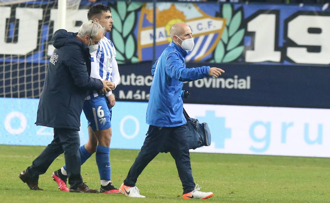 Pérez Frías examina a Ramón mientras sale del campo lesionado, con Luis Barbado delante. 
