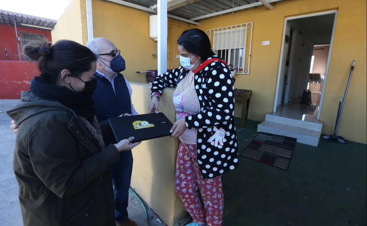 María Rodríguez, madre de tres niños, recibe un portátil de manos de Lorena Molina, educadora social, y Victoriano Giralt, de la UMA. 
