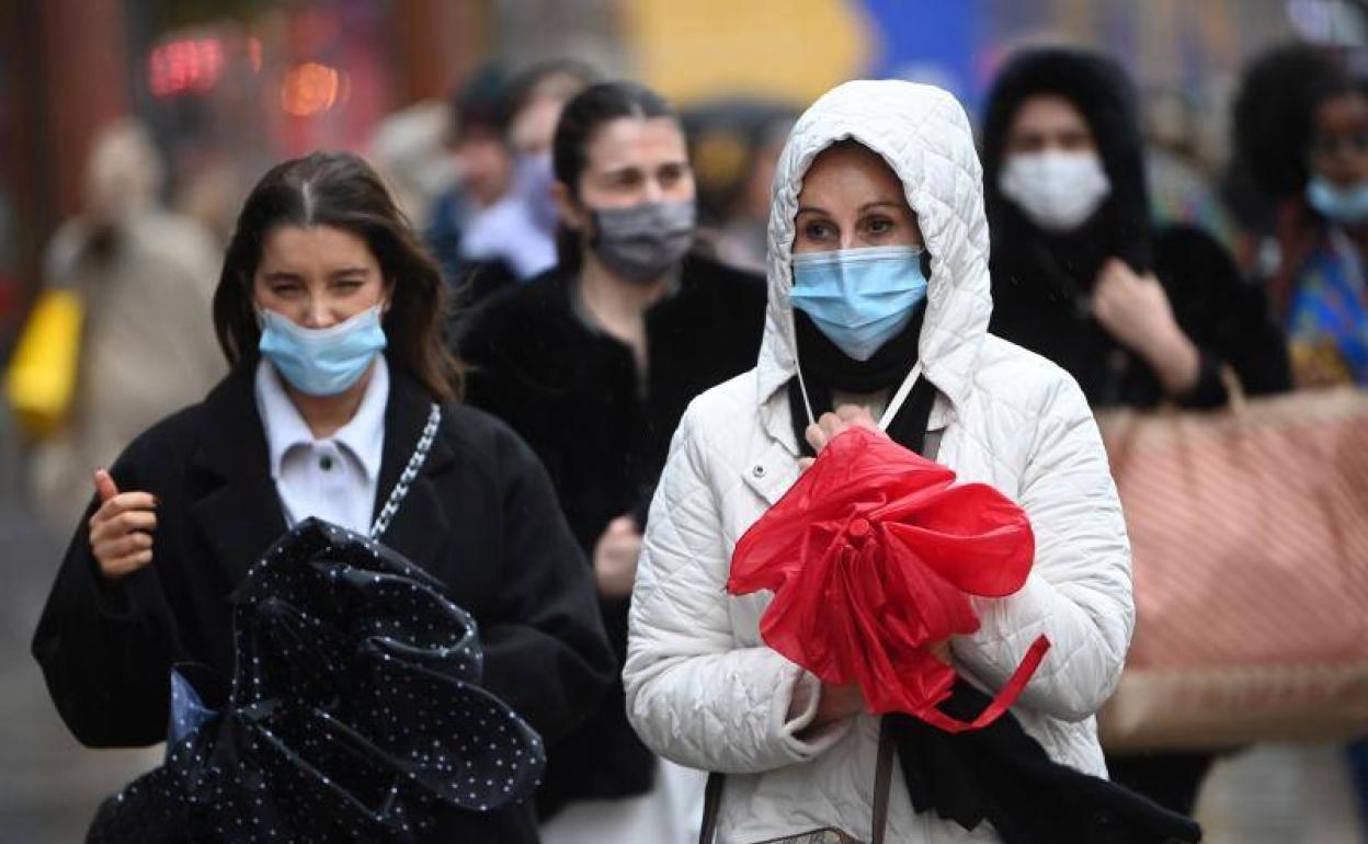 Dos mujeres pasean con mascarilla. 