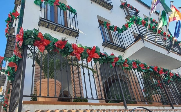 Imagen principal - Varios de los adornos navideños y el grupo de mujeres que los ha confeccionado, junto al árbol de la plaza. 