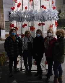 Imagen secundaria 2 - Varios de los adornos navideños y el grupo de mujeres que los ha confeccionado, junto al árbol de la plaza. 