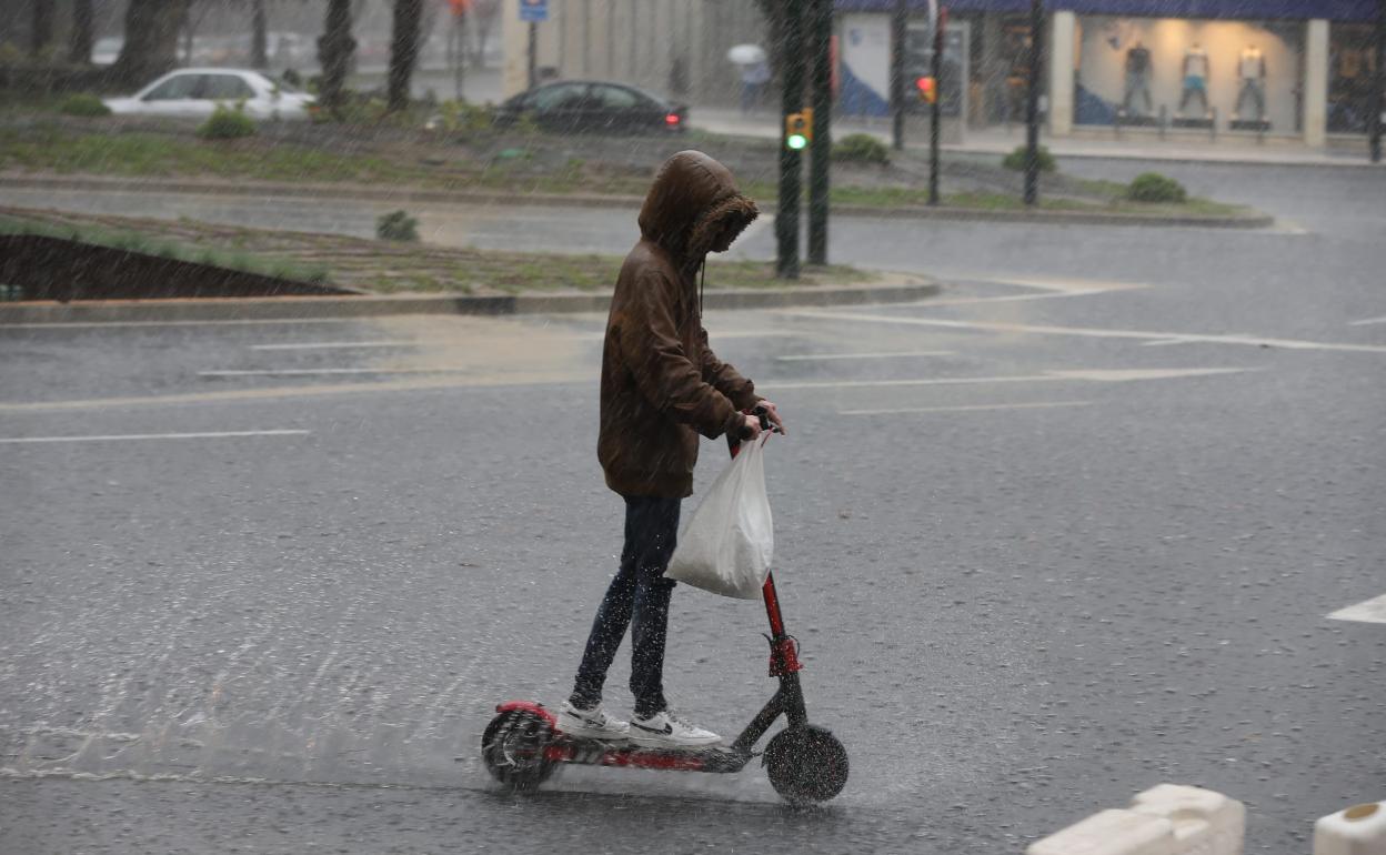 Un joven circula en patinete durante uno de los últimos episodios de lluvias en Málaga. 