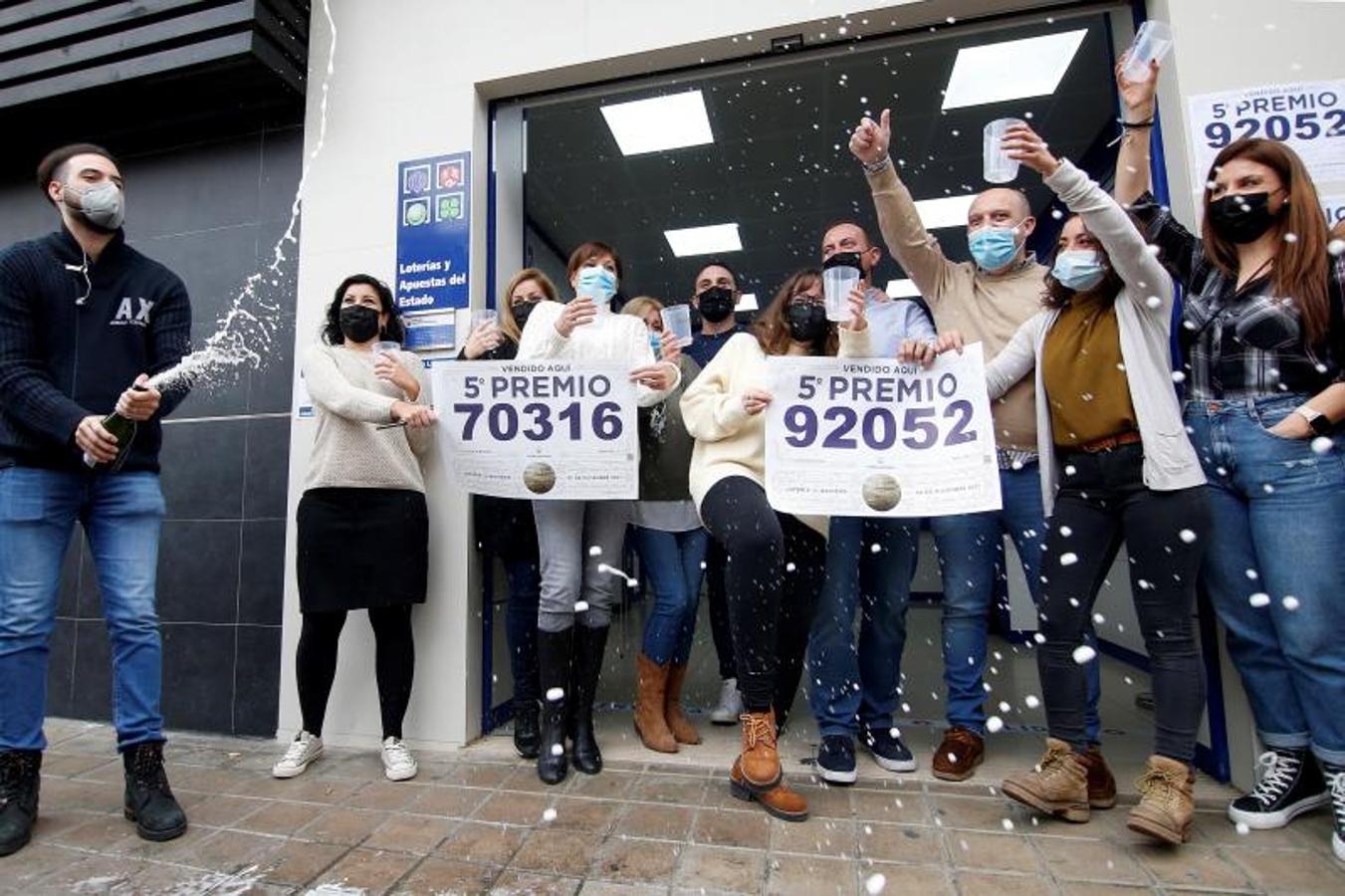 Trabajadores y vecinos de la administración número 3 de Manises (Valencia) celebran dos de los quintos. 