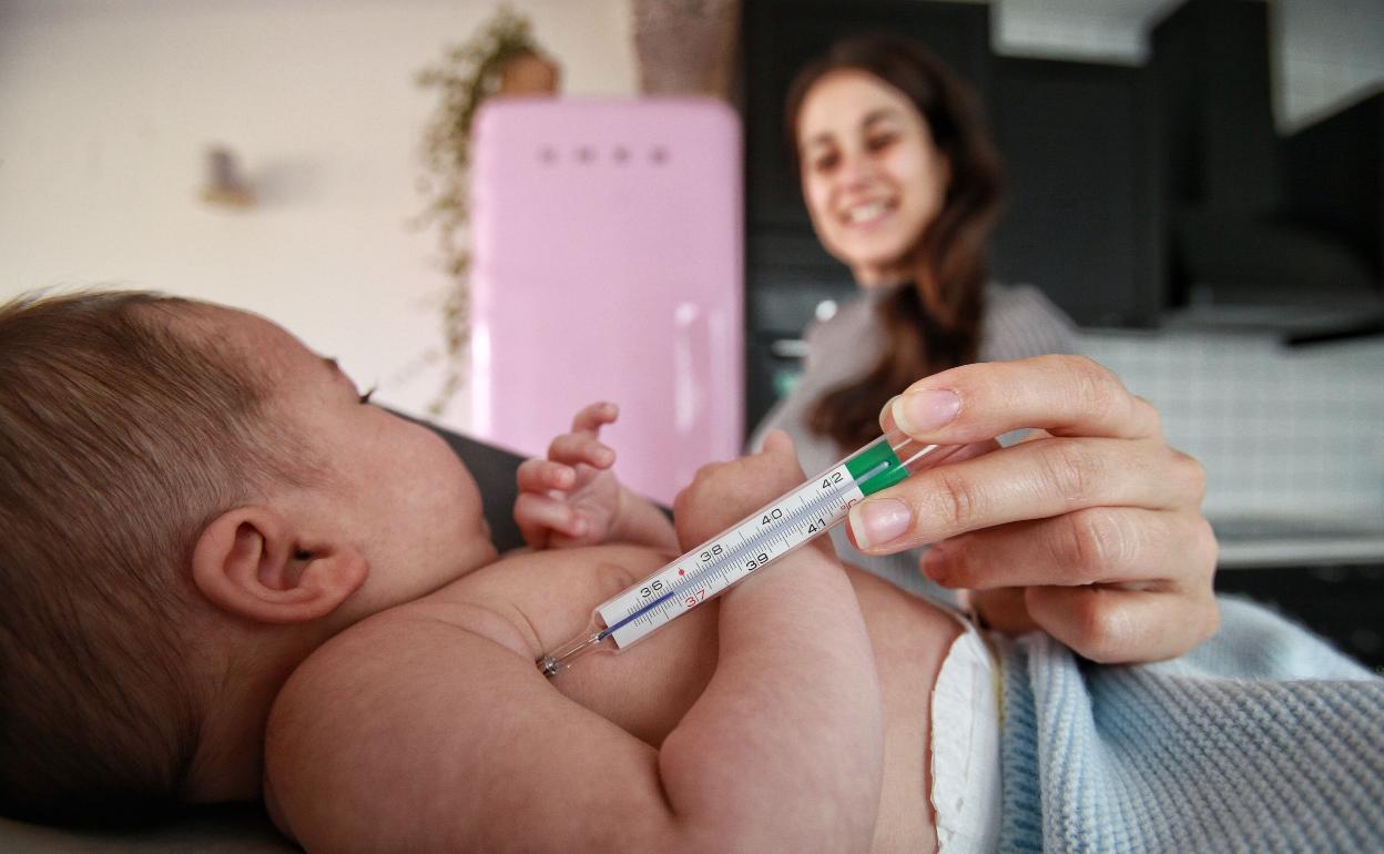 Una madre toma la temperatura a su bebé. 