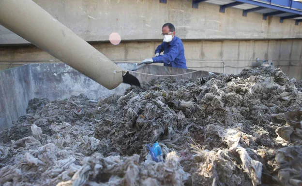 Un empleado de Emasa retira las madejas de residuos extraídas en la depuradora del Guadalhorce. 
