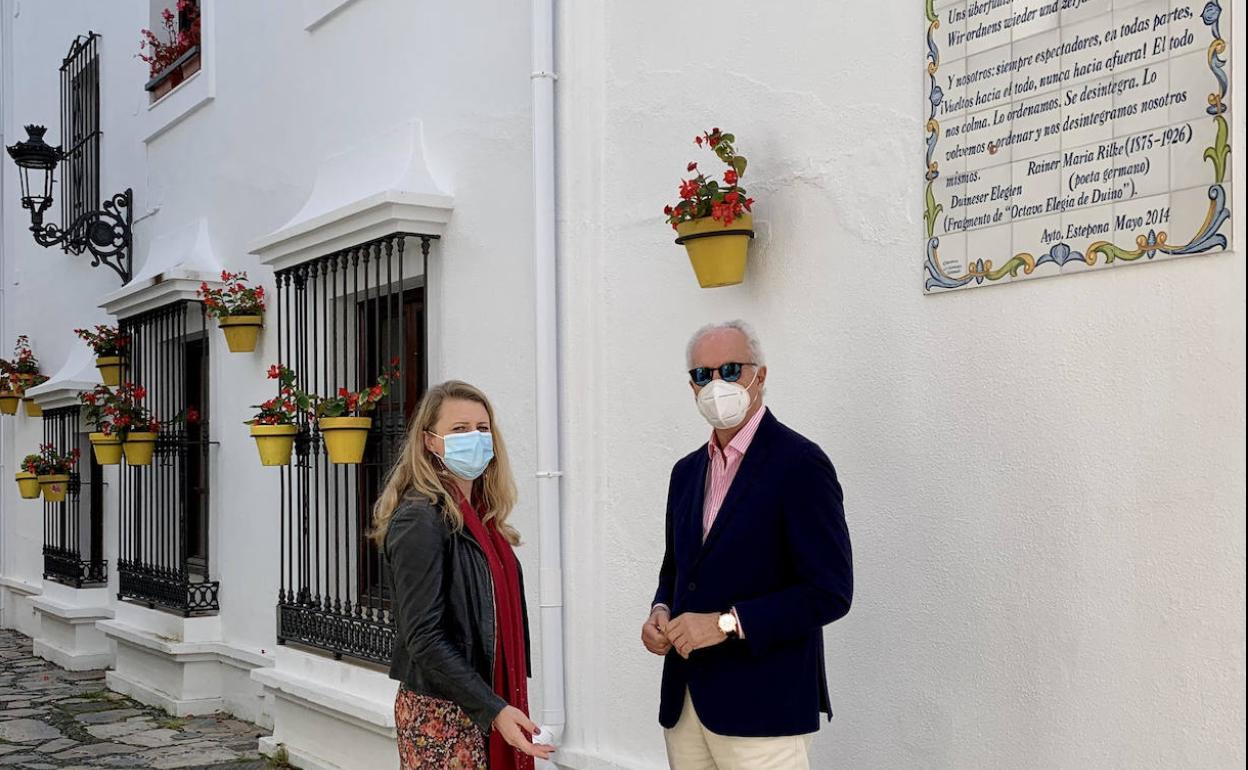 La asesora de Turismo en el Ayuntamiento de Estepona (Málaga), Aleksandra Broch (i), y el concejal de Patrimonio, Daniel García (d), junto a uno de los versos de la Ruta de la Poesía en el casco antiguo de la ciudad. 