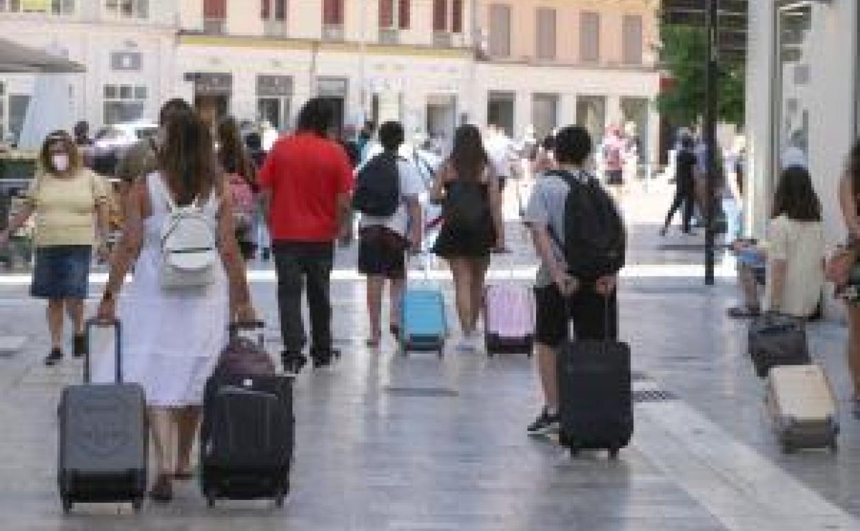 Turistas recorren el Centro de Málaga en busca del alojamiento reservado. 