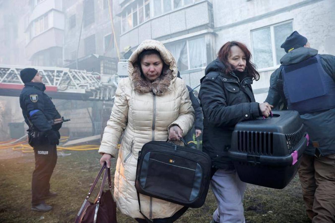 Dos mujeres huyen de un edificio que acaba de ser bombardeado.